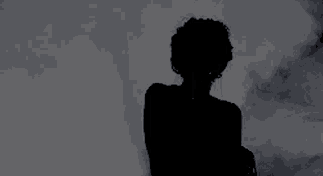 a silhouette of a woman in a dark room with smoke coming out of it