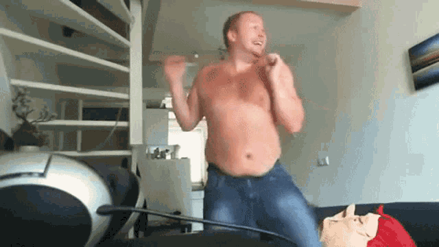 a shirtless man dancing in a living room