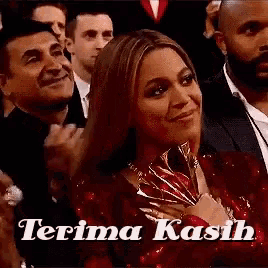 a woman in a red dress is sitting in a crowd of people with the words terima kasih above her