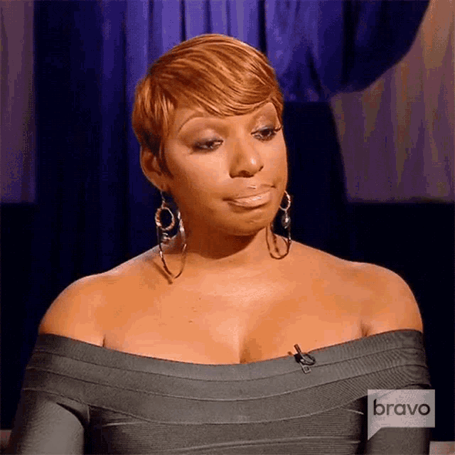 a woman wearing a gray off the shoulder dress and hoop earrings is on bravo television