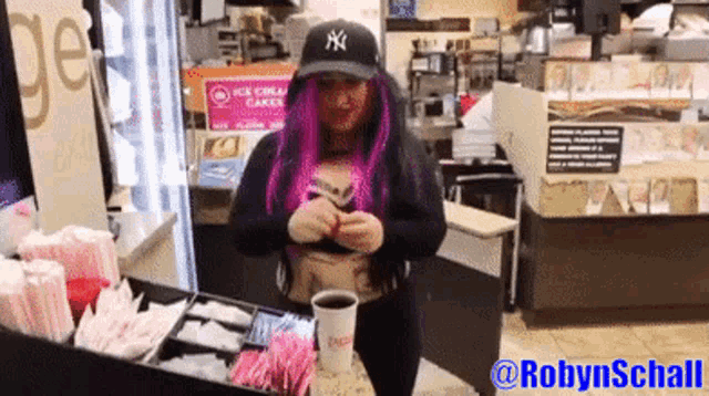 a woman with purple hair and a ny hat is behind a counter