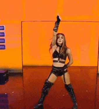 a woman in a wrestling outfit is dancing on a red floor .