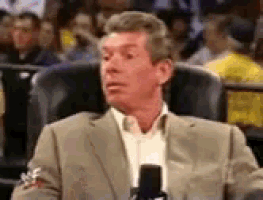 a man in a suit is sitting in a chair holding a microphone .