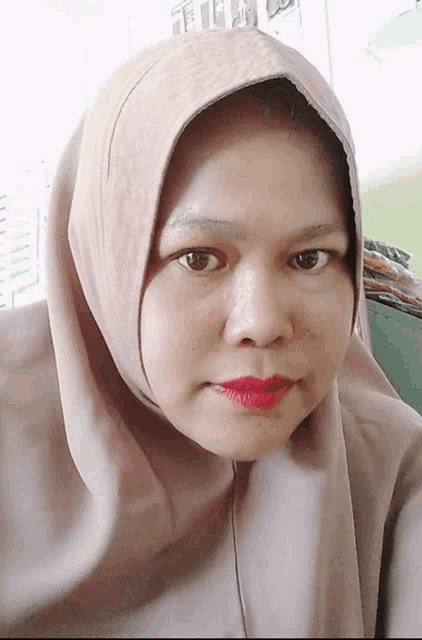 a woman wearing a hijab with red lipstick on her lips