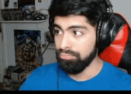 a man with a beard wearing headphones is sitting in a chair .