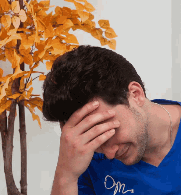 a man wearing a blue shirt that says om covering his face