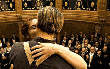 a man and woman kiss in front of a crowd of people
