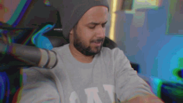a man with a beard wearing a beanie and a gray shirt with the letter n on it