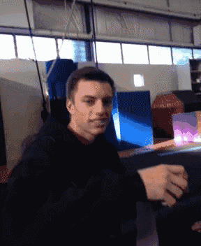 a man in a black hoodie is sitting on a couch