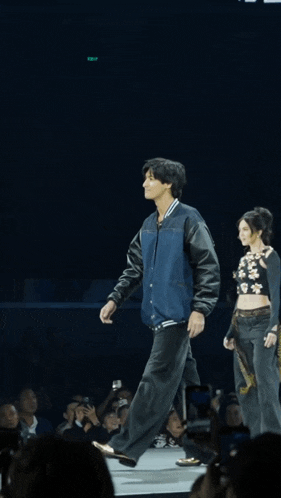 a man in a blue jacket is walking down a stage