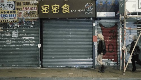 a woman walks past a store that has a sign that says eat more more