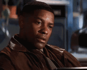 a man in a brown leather jacket is sitting at a table looking at something