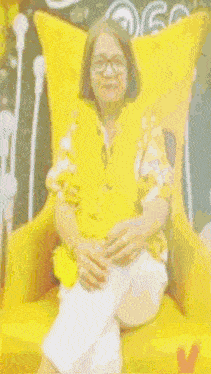 a woman is sitting in a yellow chair with the word happy on the bottom right