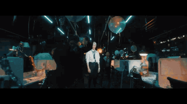a man in a tie is standing in a room with balloons