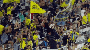 a crowd of people in a stadium with a yellow flag that says " back "
