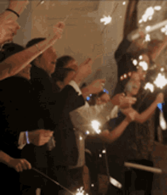 a group of people are holding sparklers up in the air