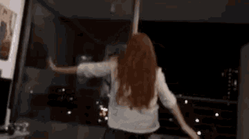 a woman with long red hair is dancing in a living room .