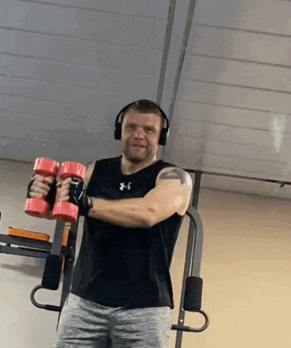 a man wearing headphones is holding a pair of red dumbbells