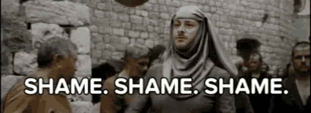 a man wearing a hijab is standing in front of a crowd of people and saying `` shame .
