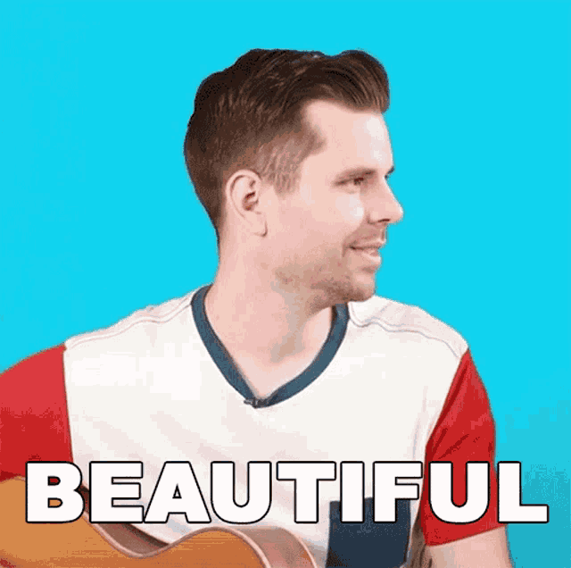 a man is holding a guitar and the word beautiful is on the screen behind him