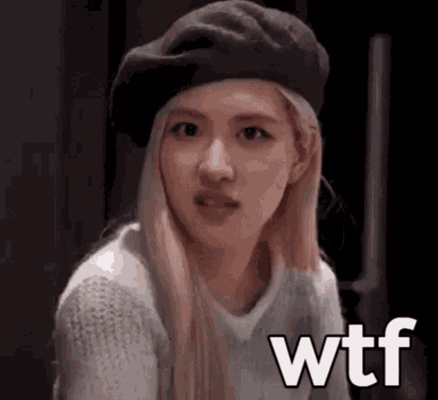 a woman wearing a beret and a sweater is making a funny face and says wtf .