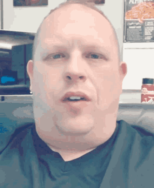 a man in a black shirt stands in front of a wall that has a pizza ad on it