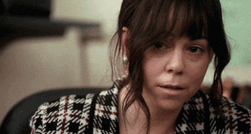 a close up of a woman 's face with a plaid shirt