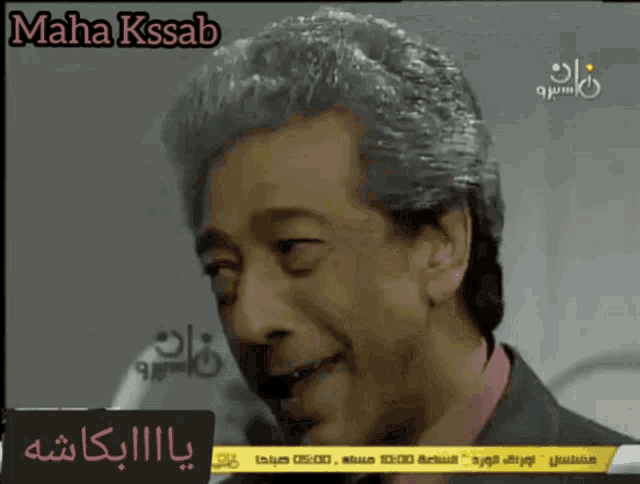 a man with gray hair is on a television screen with the name maha kssab above him