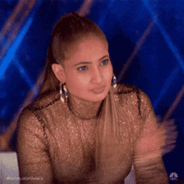a woman wearing a turtleneck and earrings is clapping her hands .