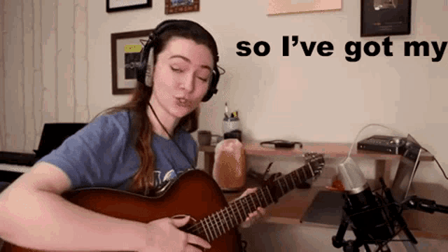 a woman wearing headphones is playing a guitar in a room .