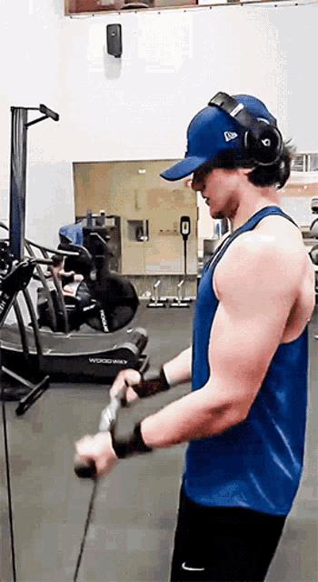 a man wearing a blue tank top and headphones is using a machine that says woodshark