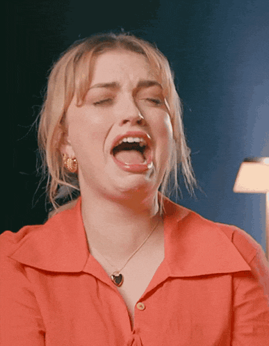 a woman in a red shirt is making a funny face with her mouth open