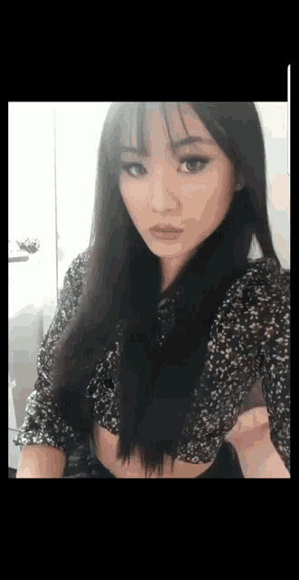 a woman with long black hair is wearing a black floral top