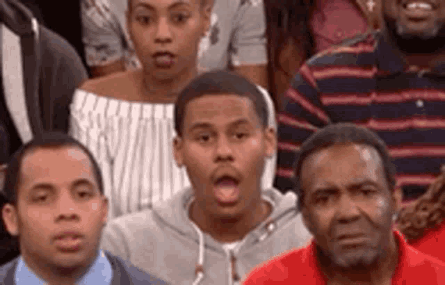 a group of people are sitting in a row and one of them is making a funny face .