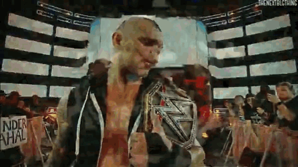 a man is holding a wrestling championship belt in front of a crowd