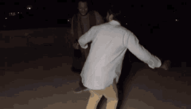 a man in a white shirt dancing with another man