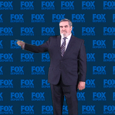 a man in a suit and tie stands in front of a fox deportes backdrop