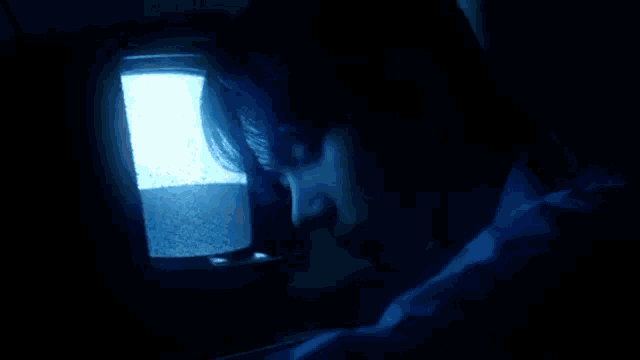 a woman is looking at a television screen in the dark .