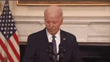 a man in a suit and tie is standing in front of two microphones with his eyes closed .
