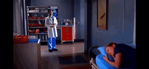 a man in a lab coat stands next to a woman laying in a hospital bed