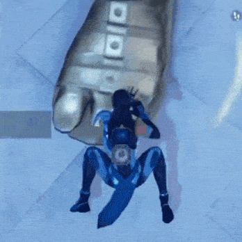 a person in a blue suit is crawling on the floor next to a large metal object .