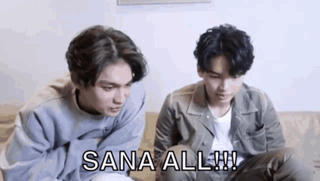 two young men are sitting next to each other on a couch and one of them is saying sana all !