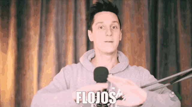 a man holding a microphone with the word flojos written on the bottom