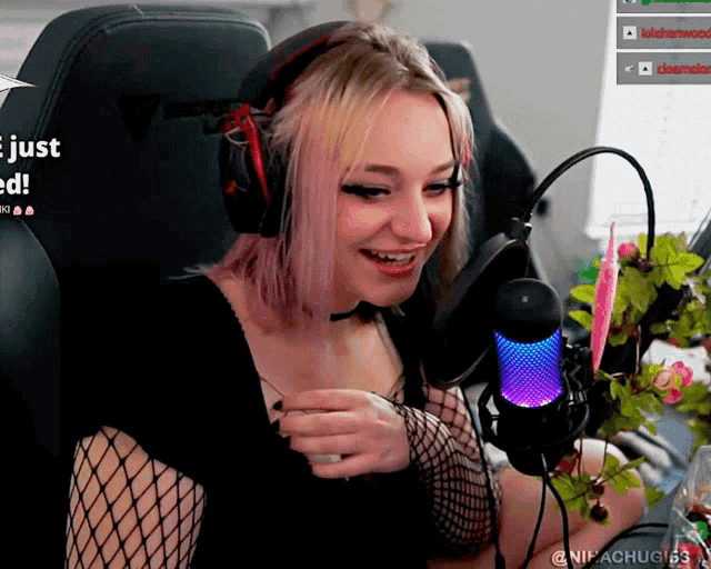 a woman wearing headphones and a fishnet top is sitting in front of a microphone and a screen that says just need