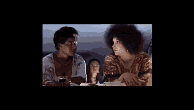 a group of women are sitting at a table with glasses of wine .
