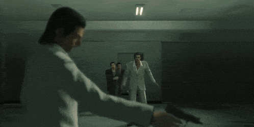 a man in a white suit is holding a gun in front of three other men