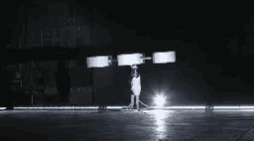 a white drone is flying in the dark with a light behind it