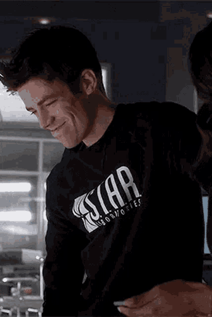 a man in a black shirt is smiling and holding a cell phone .