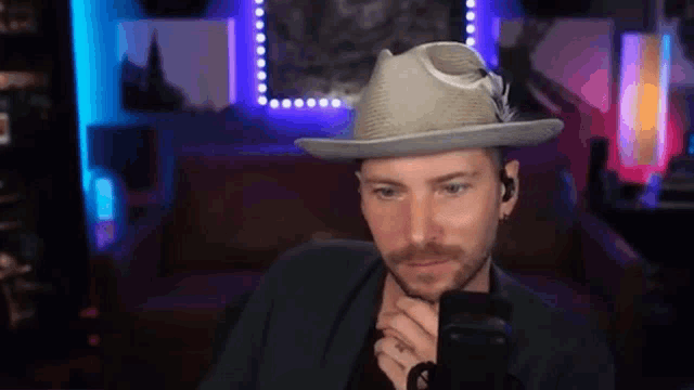a man wearing a hat and ear buds holds a microphone