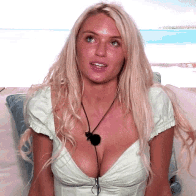 a woman with a very large breast is sitting on a couch with a microphone attached to her neck